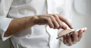 Mann in weißem Hemd mit Smartphone
