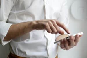 Mann in weißem Hemd mit Smartphone