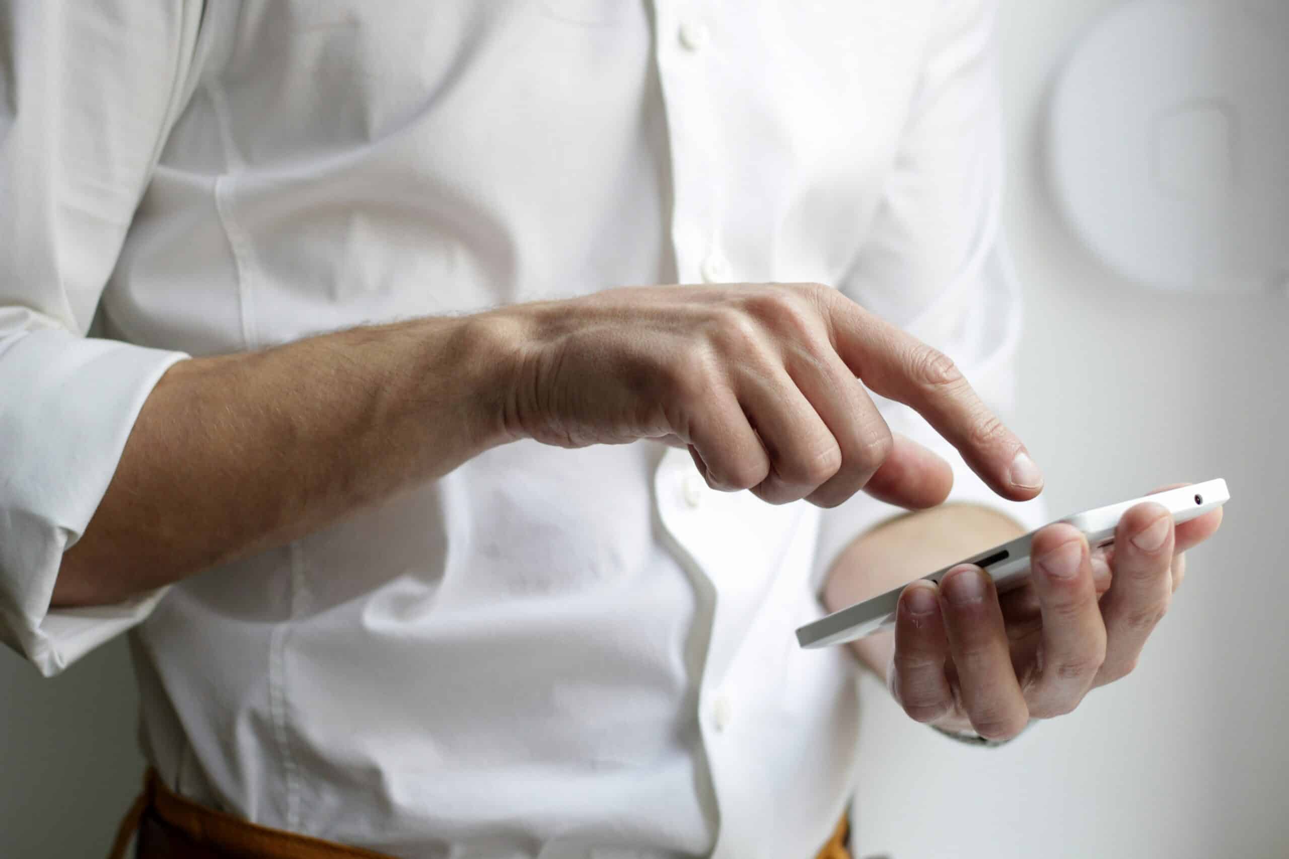 Mann in weißem Hemd mit Smartphone